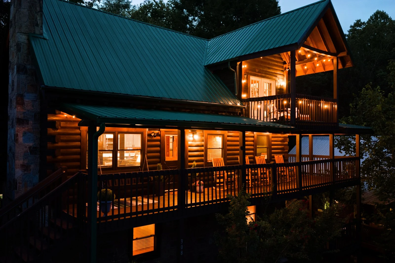 PeaksNPines at evening, with warm windows, string lights and rocking chairs along the porch